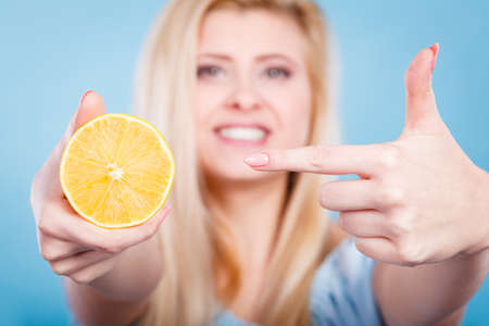 Healthy diet, refreshing food full of vitamins. Woman holding sweet delicious citrus fruit, lemon on orange.の写真素材