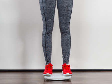 Healthy fit life style, controling body concept. Woman wearing sportswear, leggings and trainers standing on weight machine.の写真素材