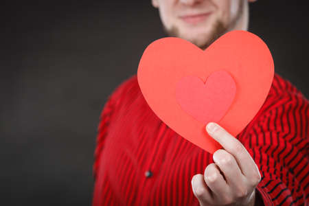 Feelings affection happiness concept. Cheerful man holding heart. Youthful energetic smiling male holding love symbol cutout.の写真素材