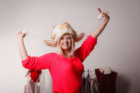 Outfit for cold days ideas, fashion and clothing concept. Attractive smiling blonde woman in wardrobe, picking clothes wearing furry winter hatの写真素材
