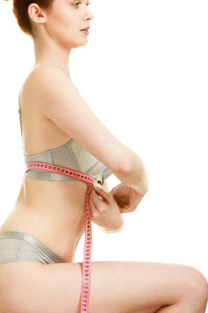 Woman slim girl in bra lingerie with red measure tape measuring her chest breasts. Isolated on white, side viewの写真素材