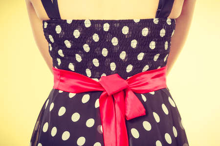 Retro, pin up, elegant and timeless clothes concept. Woman wearing retro dotted black dress with big red bowの写真素材
