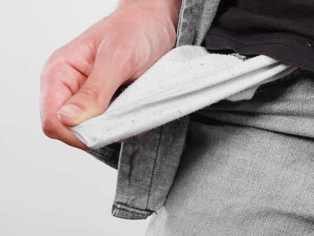 Financial difficulties, bad economy, no money concept. Young man student boy showing empty pockets, part of body male hips wearing jeans pantsの写真素材