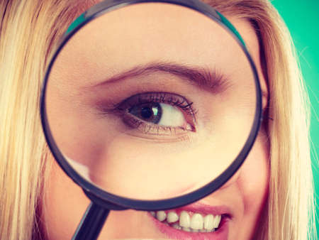Ophthalmology, spy accessories, eyesight concept. Woman looking through magnifying glass having big one eye.の写真素材