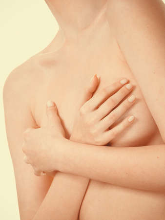Health care, medicine, female controlling for cancer. Young topless woman covering her breast with handsの写真素材