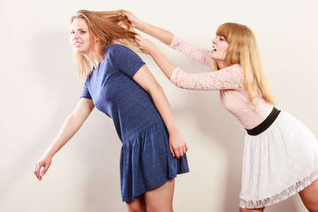 Aggressive mad women fighting each other pulling hair. Two young girls struggling win catfight. Violence.の写真素材