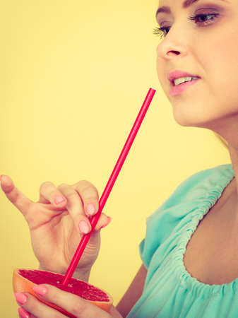 Healthy diet, refreshing food full of vitamins. Woman drinking juice from juicy fruit, redgrapefruitの写真素材
