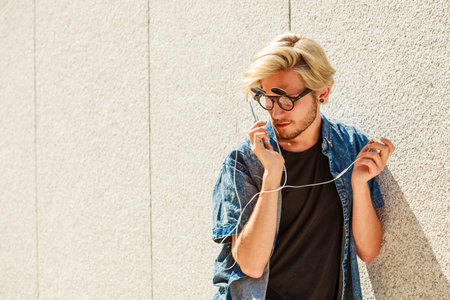 Men fashion, technology, urban style clothing concept. Hipster guy standing on city street wearing...