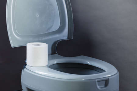 Open portable toilet bowl with paper rollの写真素材