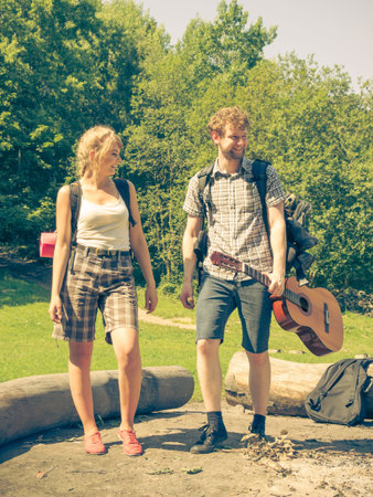 Adventure, tourism, enjoying summer time together - Hiking young couple with guitar backpack...