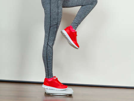 Healthy fit life style, controling body concept. Woman wearing sportswear, leggings and trainers standing on weight machine.の写真素材