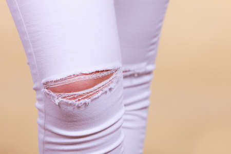 Fashion and current trends concept. Detailed closeup of white woman trousers with holes on kneesの写真素材