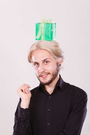 Celebration and happiness concept. Cool happy young man with green gift box on his head. Guy have crazy idea for presentの写真素材