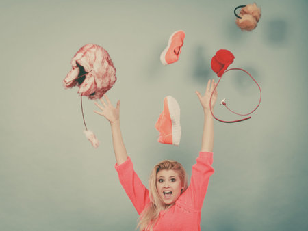 Clothing dilemmas, thinking what to wear concept. Shocked blonde woman throwing clothes above head