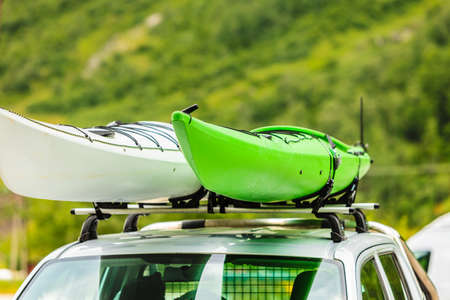 Active lifestyle sport concept. Car with two canoes white and green on top roof, mountains landscape in the backgroundの写真素材