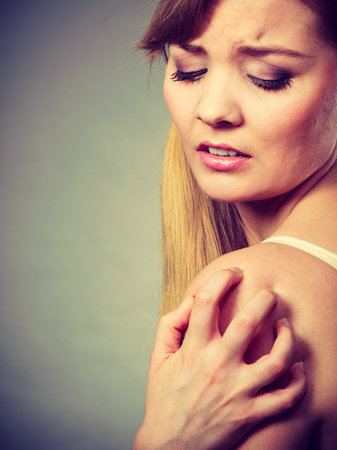 Health problem, skin diseases. Young woman scratching her itchy arm with allergy rash