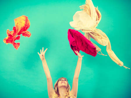 Cleaning in the closet, fashion, happiness concept. Woman throwing up lot of clothes. Clothing flying all over the placeの写真素材