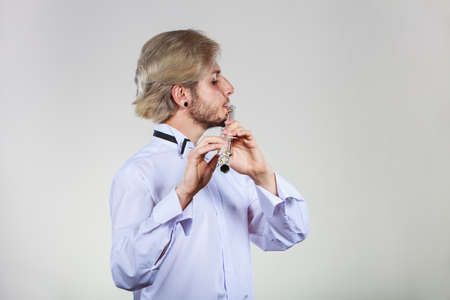 Flute music playing professional male flutist musician performer. Young elegant stylish man with instrumentの写真素材