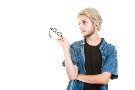 Men fashion, clothing, accessories concept. Artistic hipster guy holding glasses wearing jeans...