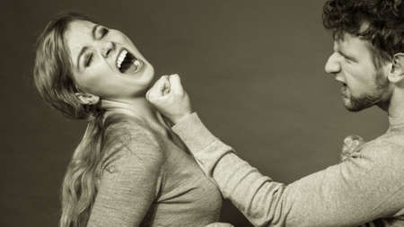 Violence against woman. Aggressive man yelling shouting on scared afraid woman. Negative relations in partnership. Expressive young male beating frightened lady.の写真素材