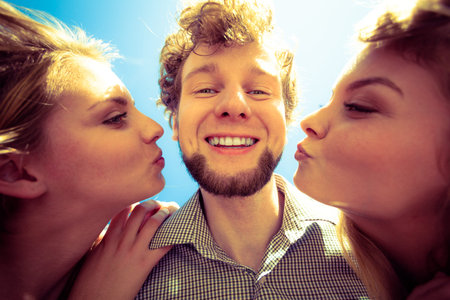 Friendship happiness love concept. Group of friends boy two girls having fun outdoor, women kissing...