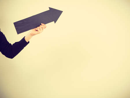 Planning, directions, choices concept. Man holding black arrow pointing right up. Indoor shot on light backgroundの写真素材