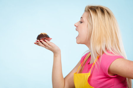 Diet, sweets, food concept. Woman holding delicious chocolate cupcake with peanut frosting about to...