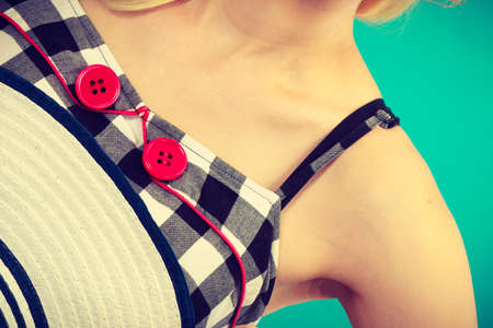 Tailoring, patterns concept. Woman wearing retro checked black and white dress with two red buttons holding sun hatの写真素材