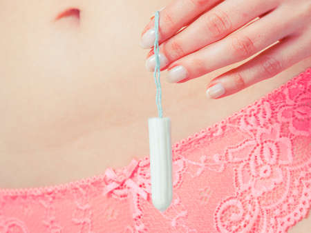 Women hygiene protection concept. Part body woman with tampon. Girl in lacy lingerie on time of menstruation monthly cycle.の写真素材