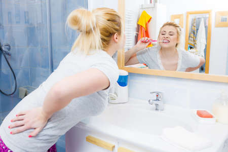 Woman brushing cleaning teeth closeup. Funny blonde girl with toothbrush in bathroom. Oral hygiene. Unusual wide angle viewの写真素材