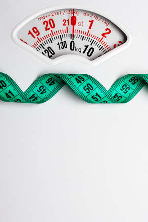 Dieting weightloss slim down concept. Closeup measuring tape on white weight scale copy space text areaの写真素材