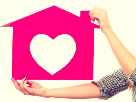 Love and dream. Woman hands holds red paper house with heart shape. New home, flat apartment concept.の写真素材