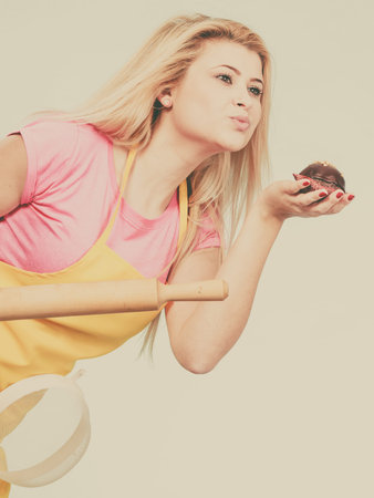 Baking tasty desserts sweets at home concept. Woman holding delicious chocolate cupcake, rolling pin...