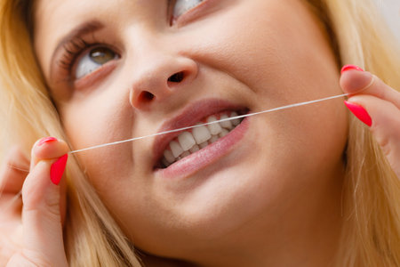Everyday oral hygiene, dentistry concept. Woman cleaning her teeth using dental floss