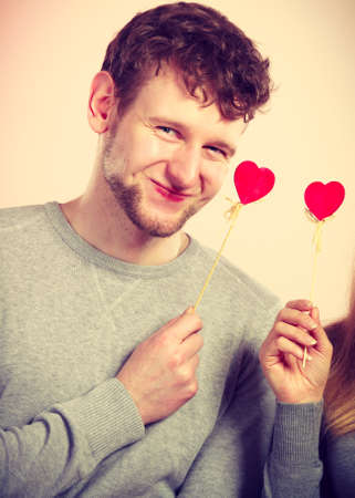 Romance relationship cheering leisure affection fun concept. Pair holding love symbols. Enamoured girl with boy showing hearts on poles.の写真素材