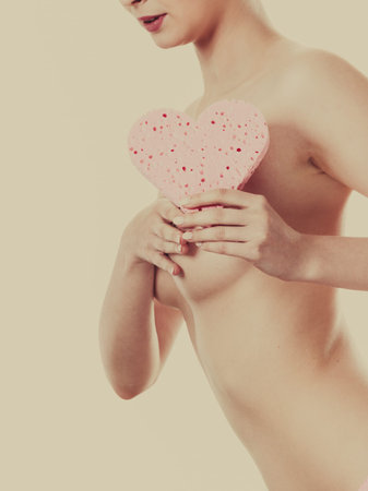 Skincare hygiene medicine and body treatment. Sensual naked woman with beautiful figure perfect skin holding pink heart shaped bath sponge in hands.Toned imageの写真素材