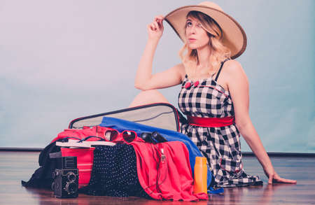 Packing for journay, traveling concept. Young woman sitting on floor with suitcase and full of things ready to be taken on summer holiday.の写真素材