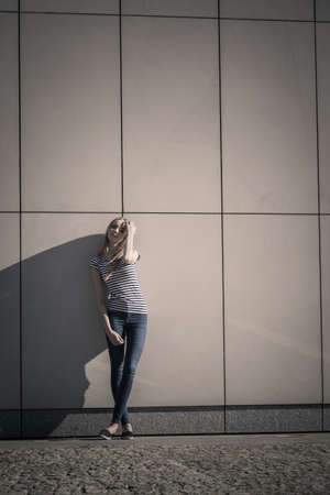 Young blonde woman in full length casual style against stone grunge wallの写真素材