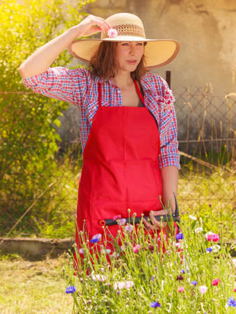 Portrait of mature smiling woman wearing big straw hat in gardenの写真素材