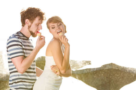 Summer holidays and happiness concept. Young couple eating ice cream outdoor city fountain in the backgroundの写真素材