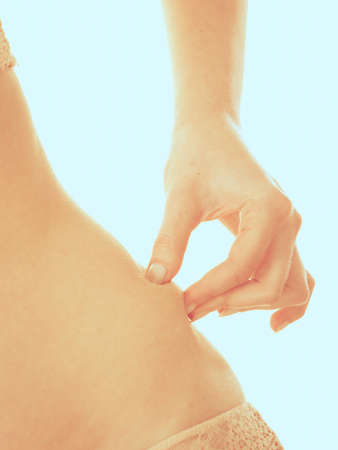 Diet and weight loss concept. Body part of slim fit girl touching pinching her belly fat. Woman after fitness aerobic and healthy food.の写真素材