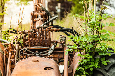 Abandoned old agricultural machinery covered with rust in high grass. Outdoor shot on sunny day.の写真素材