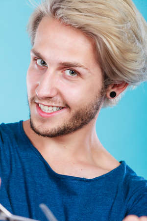 Fashion, happiness, joy concept. Happy smiling blonde man wearing blue t shirt, studio shotの写真素材