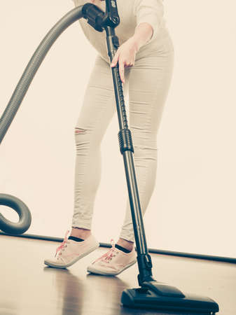 Household cleaning tools and devices, housekeeping duties concept. Woman legs and vacuum cleanerの写真素材