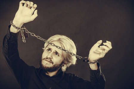 No freedom, social problems, human rights concept. Screaming furiously man with chained hands, studio shot on dark grunge backgroundの写真素材