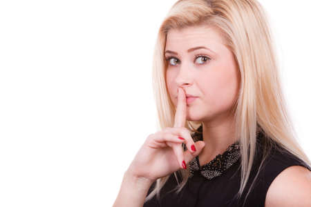 Gestures and signs concept. Attractive blonde woman making silence gesture with finger close to her mouth.の写真素材