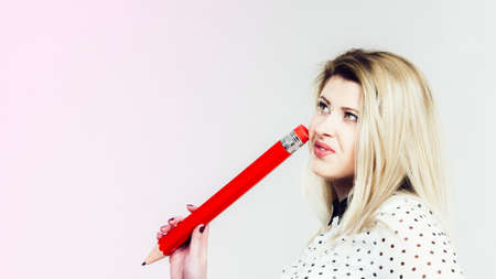 Woman hand holding big pencil. Studio shot on light background with copyspace.の写真素材