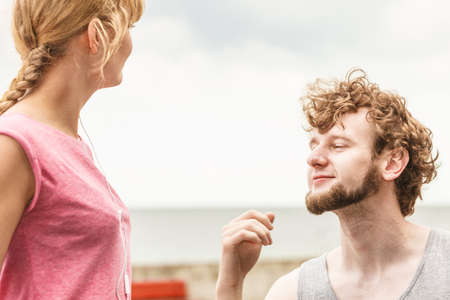 Woman and man with earphones listening to music outdoor. Young couple relaxing taking break from fitness exercise. Healthy lifestyle.の写真素材