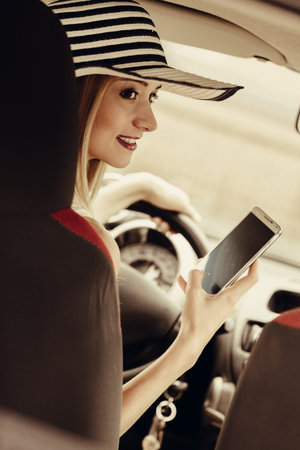 Distracted driver. Young attractive woman using mobile phone, texting or read message while driving...