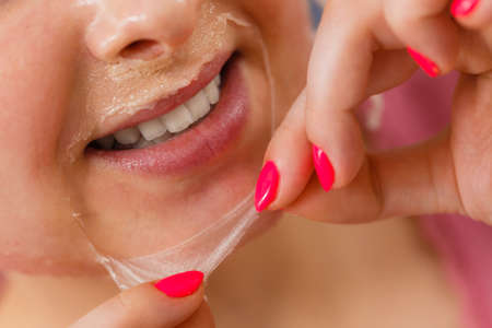 Facial dry skin and body care, complexion treatment at home concept. Woman removing gel peel off mask from faceの写真素材